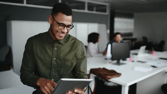 Smiling businessman scrolling on tablet