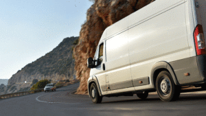 Small business white van driving down the highway with mountain terrain in the background