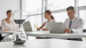 Hourglass on a table with corporate workers in the background